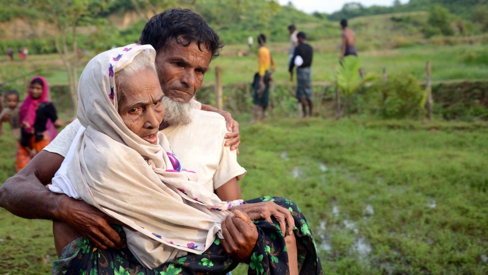 বৃদ্ধা মাকে কোলে নিয়ে উখিয়া সীমান্ত দিয়ে বাংলাদেশে ঢুকছেন এক রোহিঙ্গা শরণার্থী