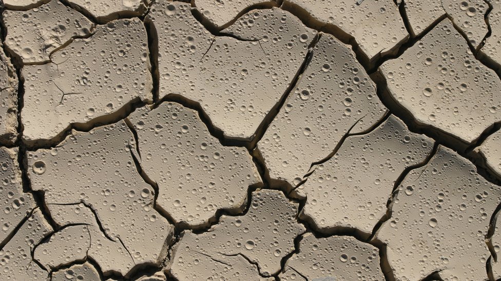 Dry, cracked earth with raindrops Dry, cracked earth with raindrops