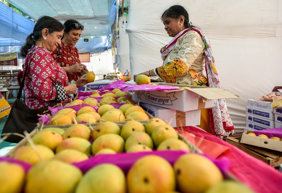 একটি বাজারে দুইজন নারী আম কিনছেন