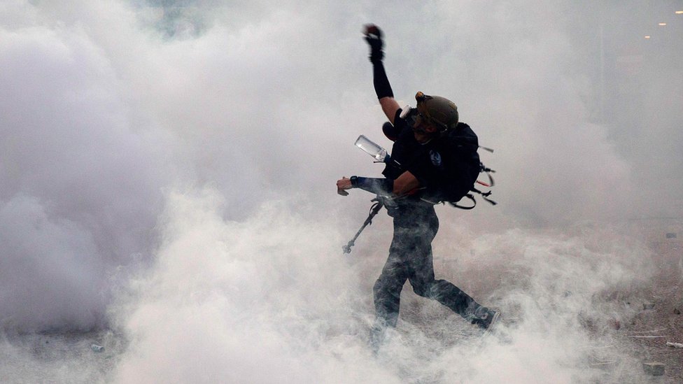 A protester throws bricks at the police after they fired tear gas during a general strike in Hong Kong on 5 August 2019 A protester throws bricks at the police after they fired tear gas during a general strike in Hong Kong on 5 August 2019