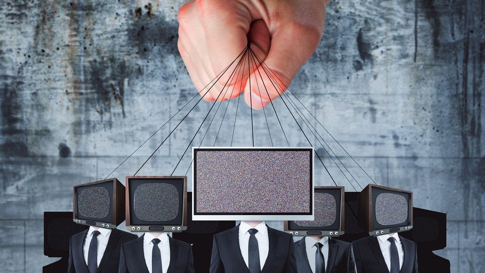 A hand gripping a bunch of strings tied to television sets