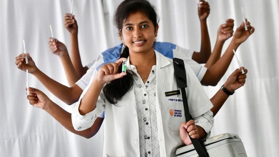 দুর্গা প্রতিমার ভঙ্গিমায় স্বাস্থ্য কর্মীরা। সামনের স্বাস্থ্য কর্মীর হাতে টিকার ভায়াল দুর্গা প্রতিমার ভঙ্গিমায় স্বাস্থ্য কর্মীরা। সামনের স্বাস্থ্য কর্মীর হাতে টিকার ভায়াল