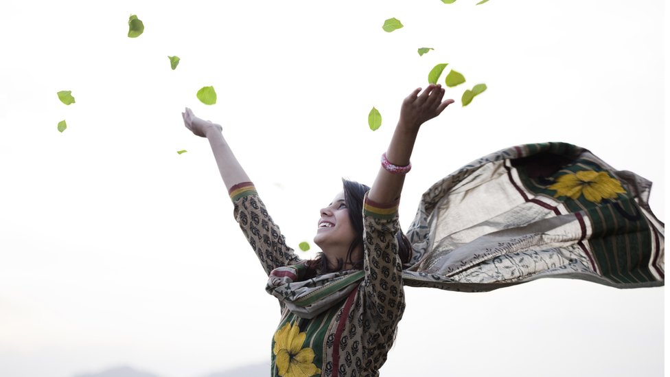 একটি মেয়ে আকাশে পাতা ওড়াচ্ছে।